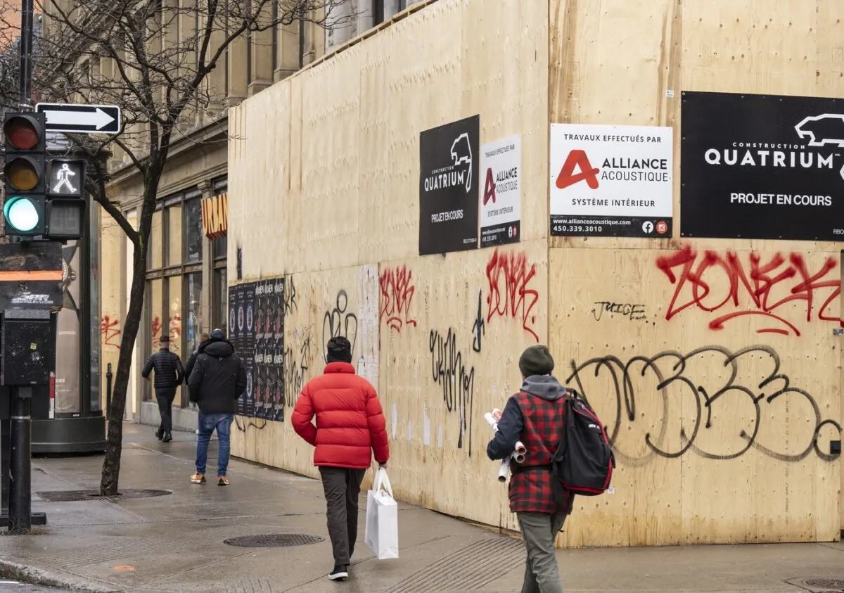 Shoppers walk past a boarded up storefront on Ste-Catherine Street in downtown Montreal, on Dec. 19, 2023. (The Canadian Press/Christinne Muschi)
