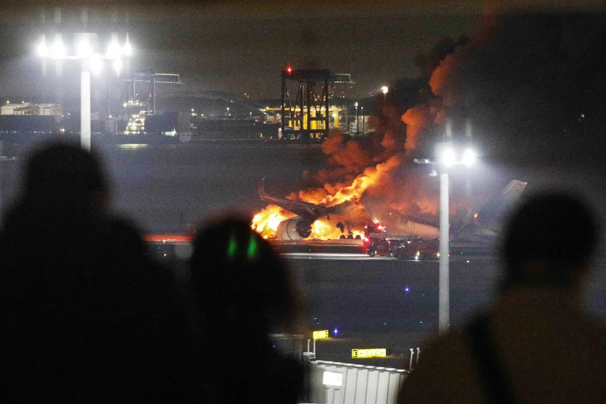 This photo provided by Jiji Press shows people on an observation deck looking at a Japan Airlines plane on fire on a runway of Tokyo's Haneda Airport on Jan. 2, 2024. (JIJI PRESS/AFP/Getty Images)