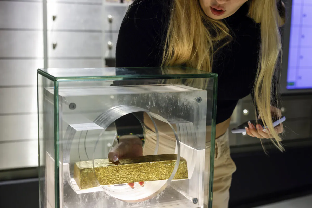 A woman lifts a gold bar at the National Bank of Poland, the country's central bank, in Warsaw, Poland, on Nov. 13, 2022. . (AP Photo / Michal Dyjuk)