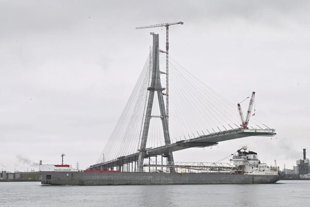 The freighter Manitowoc makes its way down the Detroit River past continuing construction on the Gordie Howe International Bridge, Canadian span, in Detroit on Dec. 29, 2023. (Daniel Mears/Detroit News via AP)