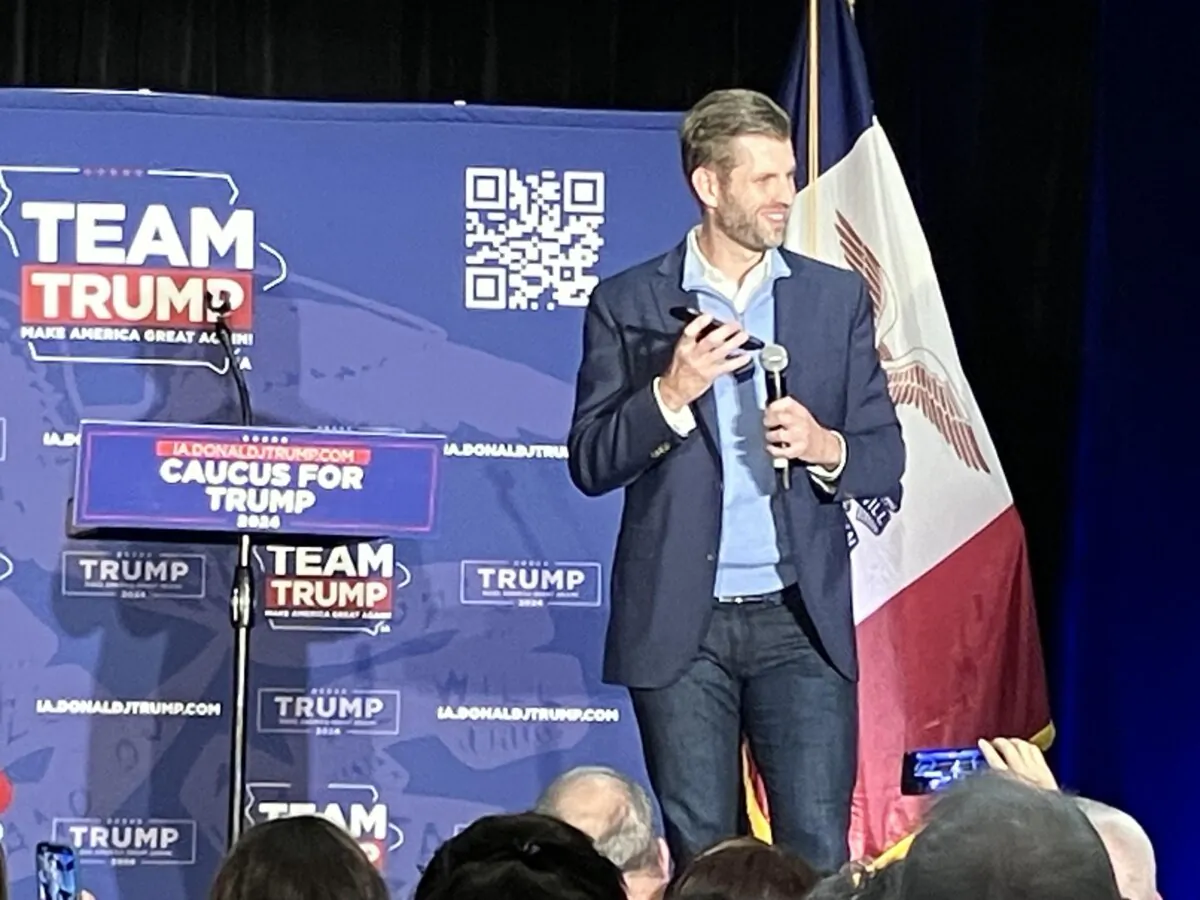 Eric Trump smiles while holding his cellphone against a microphone so the audience can hear his father, former President Donald Trump, while his son  campaigned for him at the Future Farmers of America Enrichment Center in Ankeny, Iowa, on Jan. 4, 2024. (Janice Hisle/The Epoch Times)