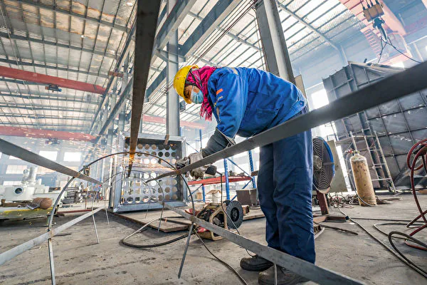 An employee at a factory is engaged in producing building material processing equipment in Nantong City, Jiangsu, on Dec. 5, 2023. (STR / AFP)