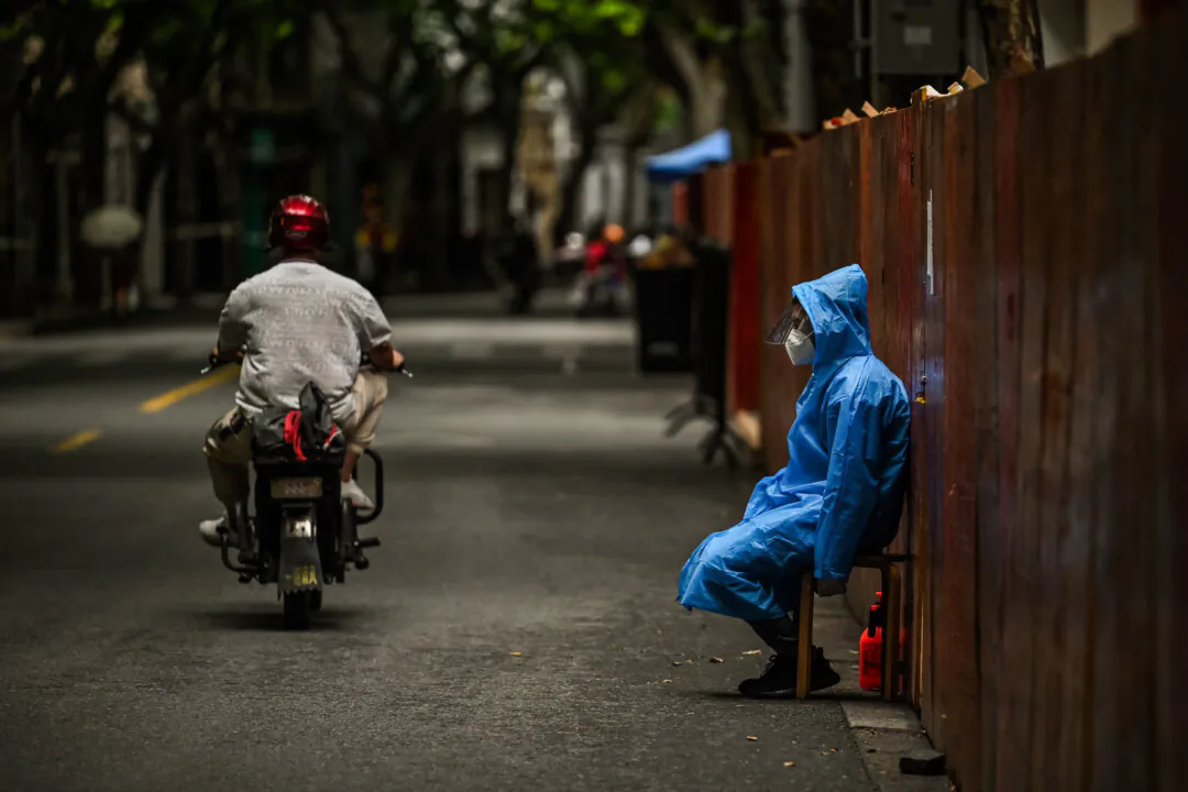 A worker sits next to a fence close to a residential area during the COVID-19 lockdown in the Huangpu district of Shanghai on June 10, 2022. (Hector Retamal /AFP via Getty Images)