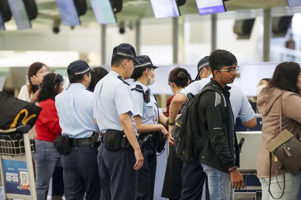 Police question a passenger at the departure hall of Hong Kong International Airport on April 5, 2023. (Adrain Yu/The Epoch Times)