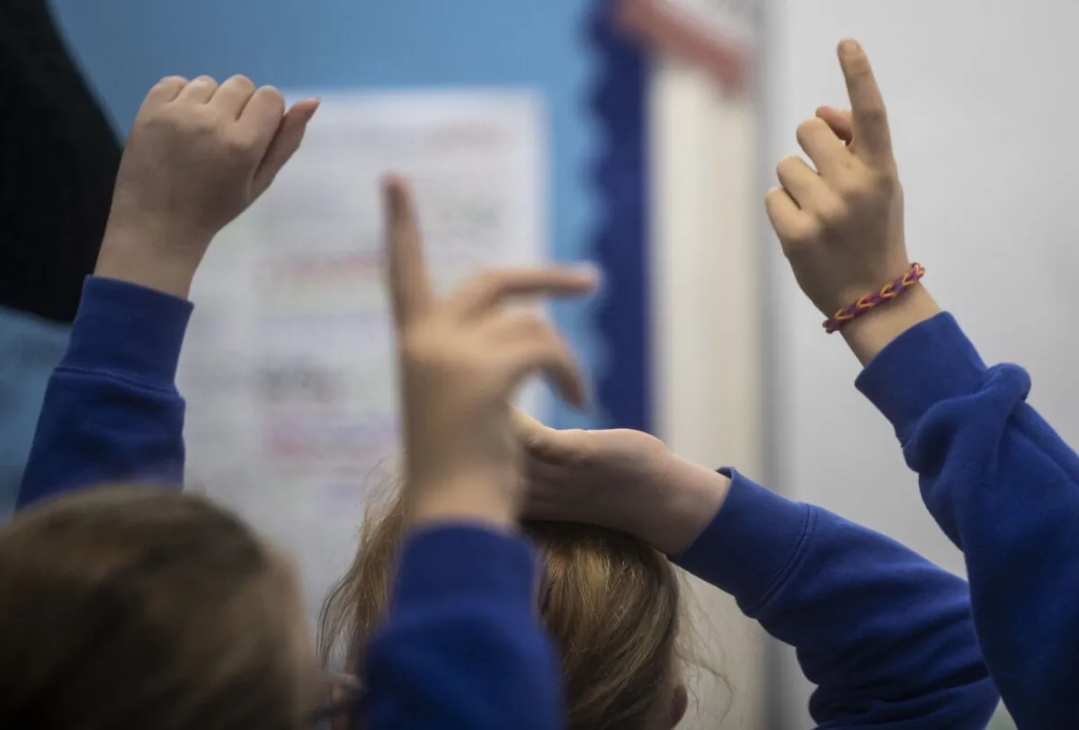 Undated photo of pupils raising their hands during a class. (PA)