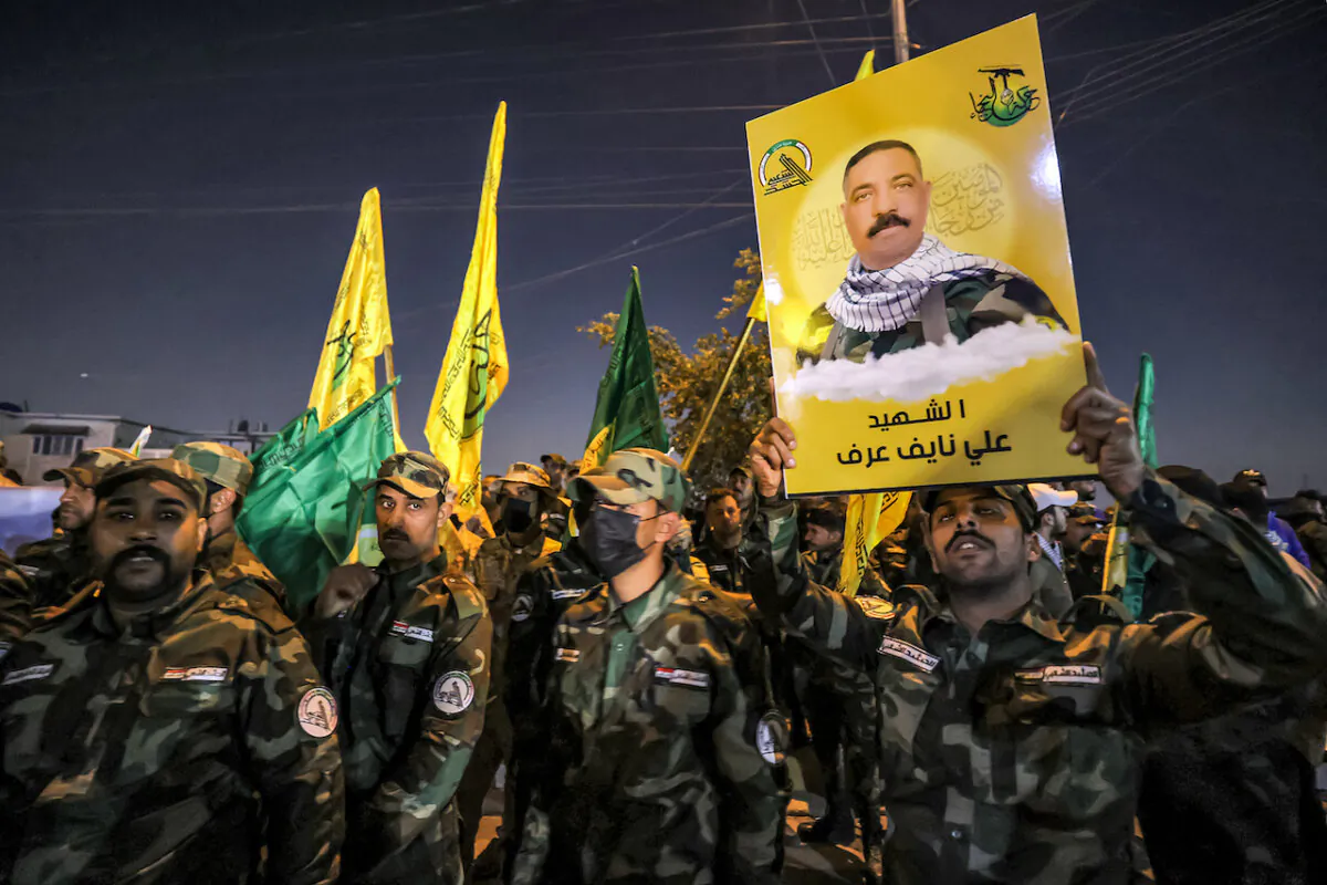 A member of Iraq's Popular Mobilisation Forces (PMF) paramilitaries holds a sign identifying one of the group's slain members during the funeral at the PMF headquarters in Baghdad on January 4, 2024. (Ahmad al-Rubaye/AFP via Getty Images)