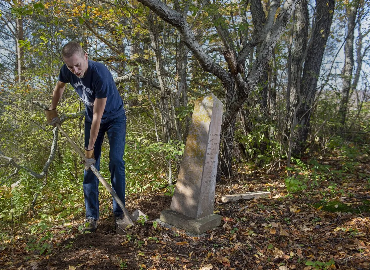 Steve Skafte, a photographer and writer based in Nova Scotia's Annapolis Valley, works to stabilize a grave marker in a small, long-abandoned cemetery in West Paradise, N.S. on Oct. 21, 2021. (The Canadian Press/Andrew Vaughan)