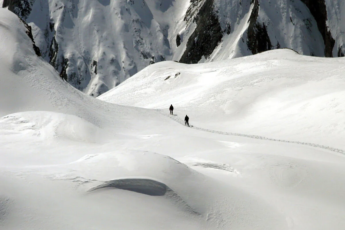 Two mountain hikers are dwarfed by the winter landscape of the Formazza Valley, northern Italy, on April 11, 2004. (Fabio Polimeni/AP Photo)