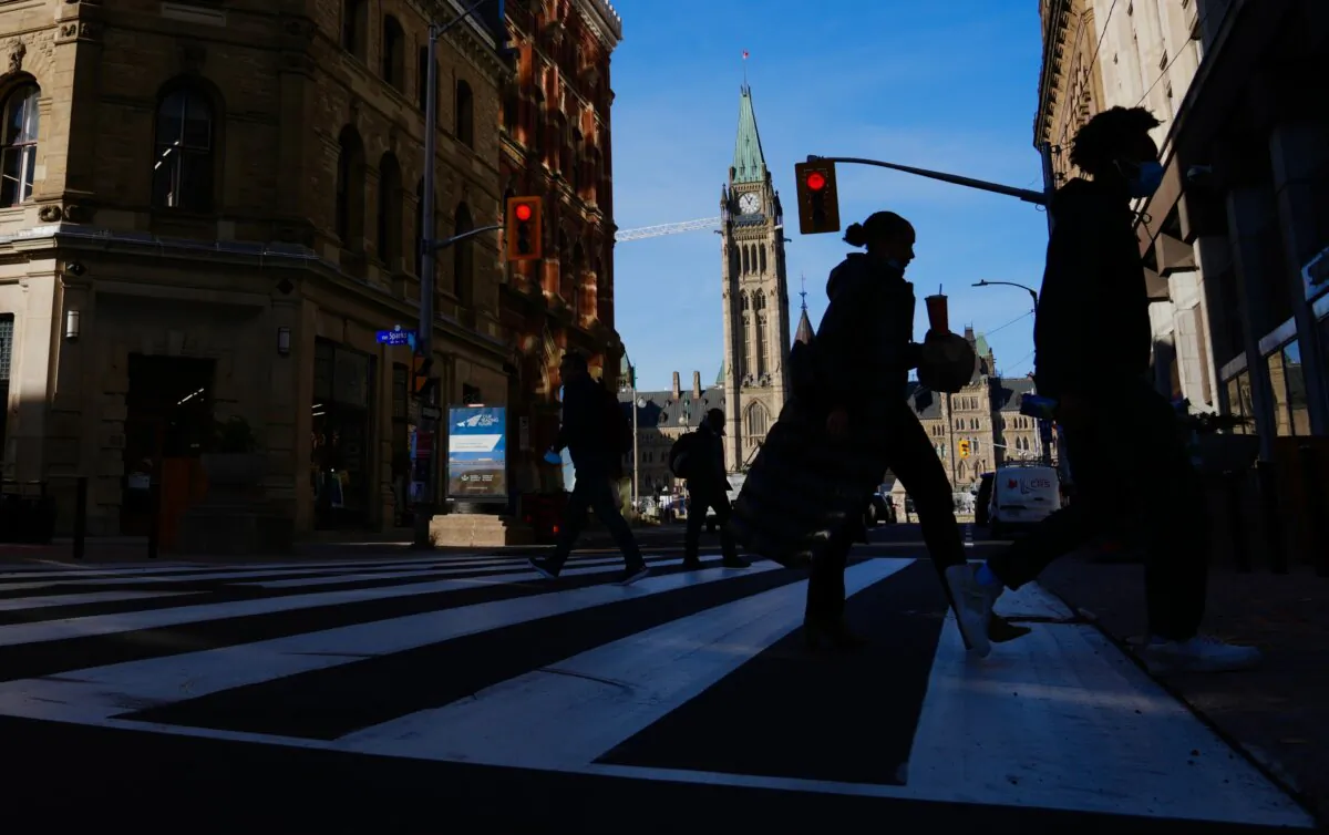 The Canadian flag flies on the Peace Tower of Parliament Hill as pedestrians make their way along Sparks Street Mall in Ottawa on Nov. 9, 2021. (The Canadian Press/Sean Kilpatrick)