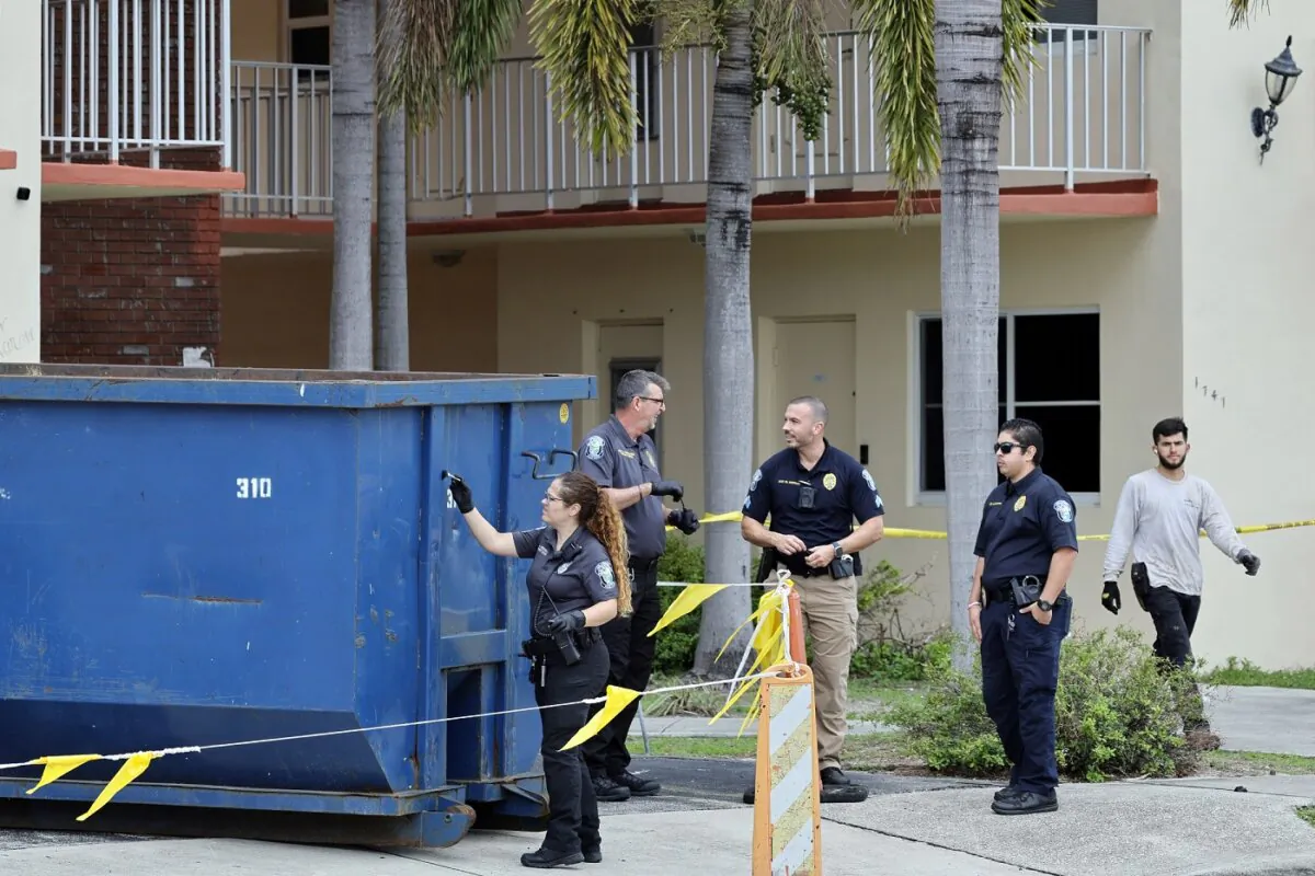 Investigator dusts for fingerprints at a large trash bin outside of an apartment complex in Hollywood, Fla., on Jan. 8, 2024, where construction workers found a dead baby. (Amy Beth Bennett/South Florida Sun-Sentinel via AP)