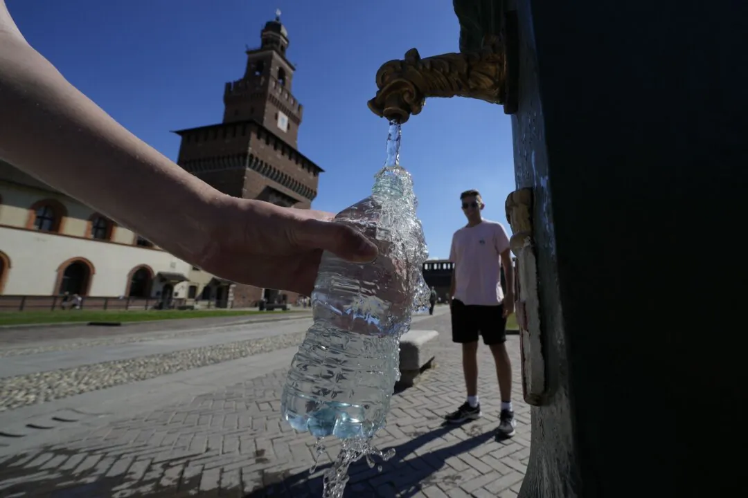 Tourists fill plastic bottles with water from a public fountain at the Sforzesco Castle in Milan on June 25, 2022. (Luca Bruno/AP Photo)