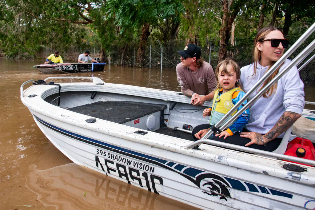 People prepare to return to their flooded residential area by boat in Cairns on Dec. 18, 2023. (Photo by Brian Cassey / AFP via Getty Images)