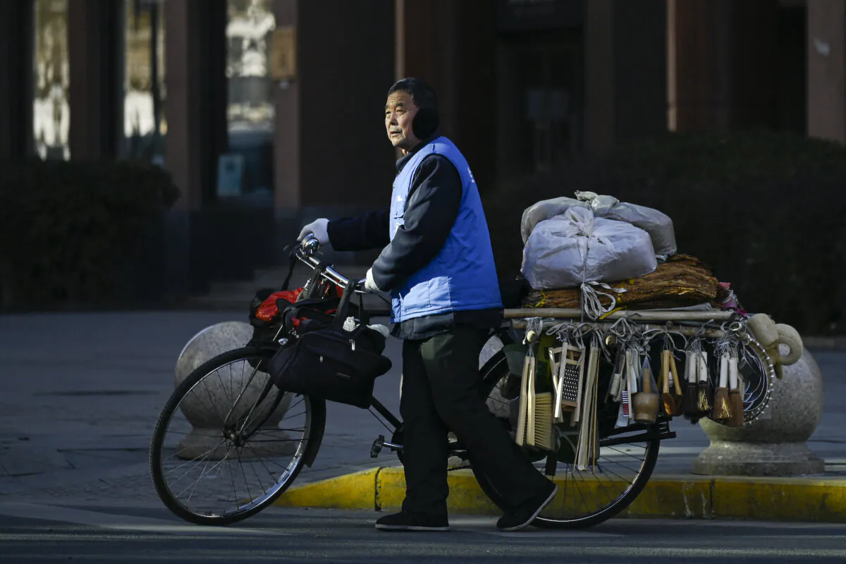 A vendor, pushing his bicycle, prepares to cross a street in Beijing on Jan. 3, 2024. (Wang Zhao/AFP via Getty Images)