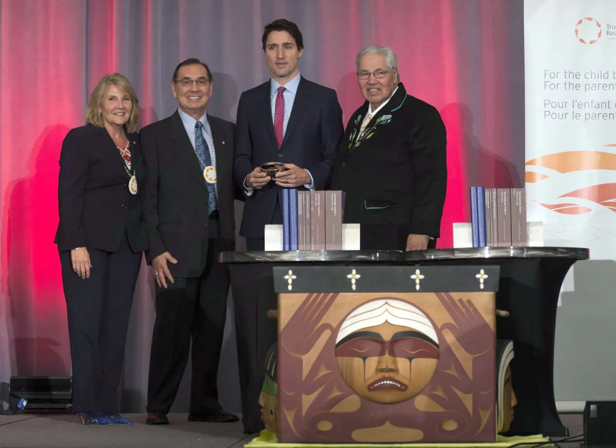 Commissioner Justice Murray Sinclair (R), Commissioner Chief Wilton Littlechild, and Commissioner Marie Wilson pose for a photo with Prime Minister Justin Trudeau after presenting him with a copy of the final Truth and Reconciliation report, in Ottawa on Dec. 15, 2015. (The Canadian Press/Adrian Wyld)