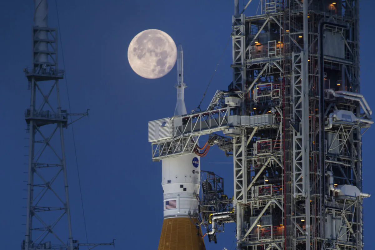 A full moon is seen behind the Artemis I Space Launch System (SLS) and Orion spacecraft, atop the mobile launcher, are prepared for a wet dress rehearsal to practice timelines and procedures for launch, at Launch Complex 39B at NASA's Kennedy Space Center in Florida on June 14, 2022. (Cory Huston/NASA via AP)
