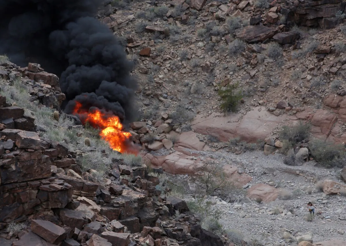 A survivor, (lower R), walks away from the scene of a deadly tour helicopter crash along the jagged rocks of the Grand Canyon, in Ariz., on Feb. 10, 2018. (Teddy Fujimoto via AP)