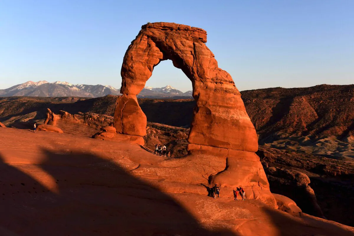 Hikers walk beside the Delicate Arch at sunset in the Arches National Park near Moab, Utah on April 21, 2018. - The park which has over 2000 arches that were formed over 100 million years by a combination of water, ice, extreme temperatures and underground salt movement. (Photo by Mark Ralston / AFP)        (Photo credit should read MARK RALSTON/AFP via Getty Images)