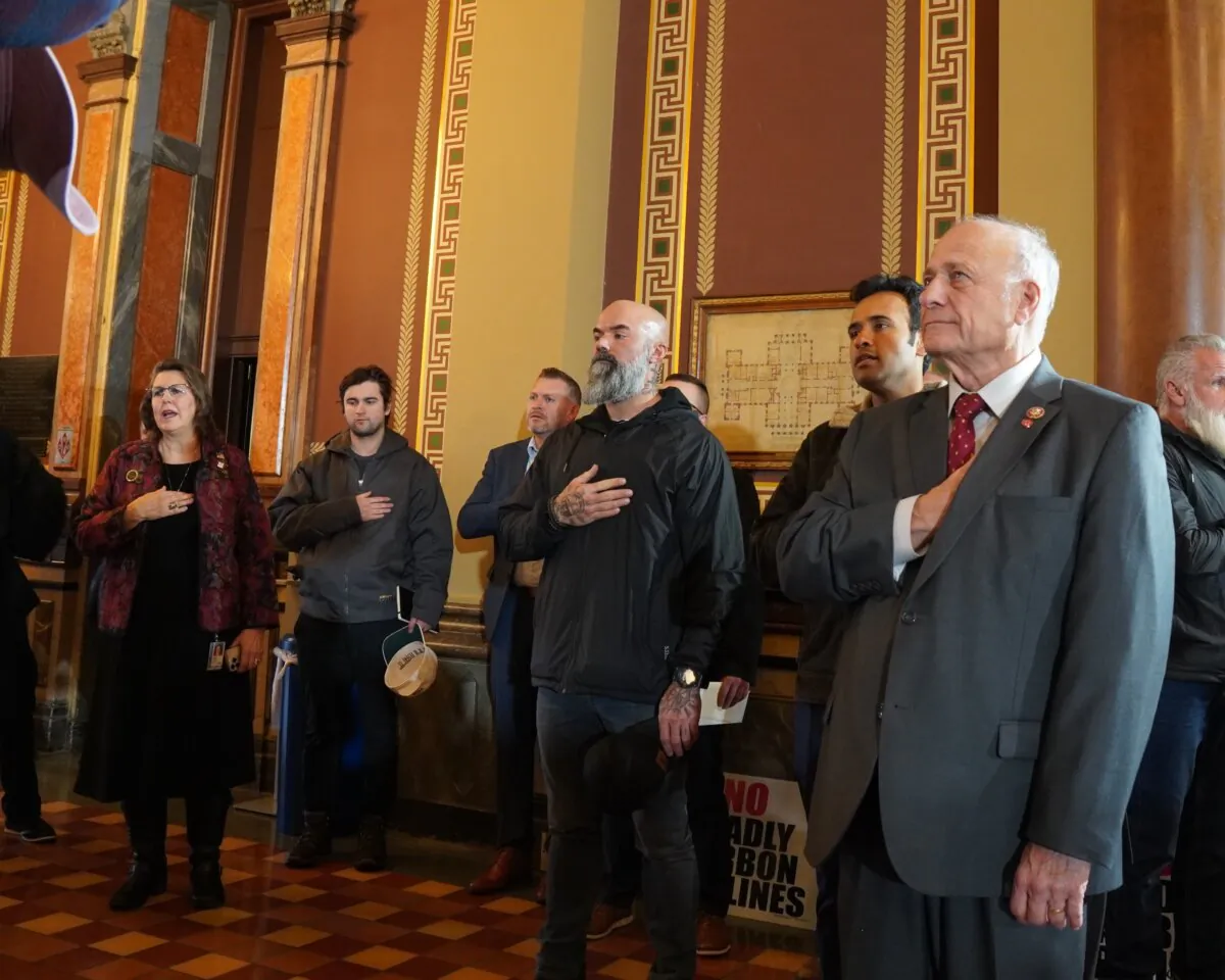 Vivek Ramaswamy and Steve King listen to the national anthem in the Iowa State Capitol on Jan. 10, 2024. (Nathan Worcester/The Epoch Times)