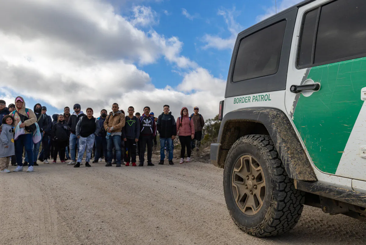 Migrants gather after crossing the United States border wall in Jacumba, Calif., on Jan. 10, 2024. (John Fredricks/The Epoch Times)