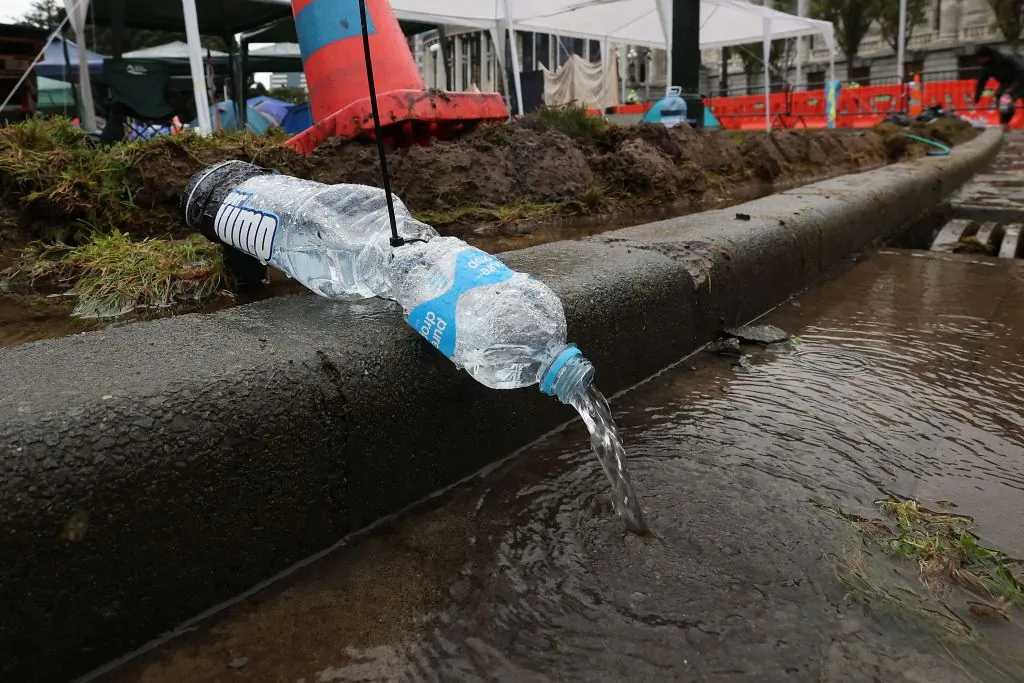 Pipes made of bottles channel water after the Speaker of Parliament ordered the sprinklers to be turned on all night in the grounds of Parliament in Wellington, New Zealand, on Feb. 12, 2022. (MARTY MELVILLE/AFP via Getty Images)