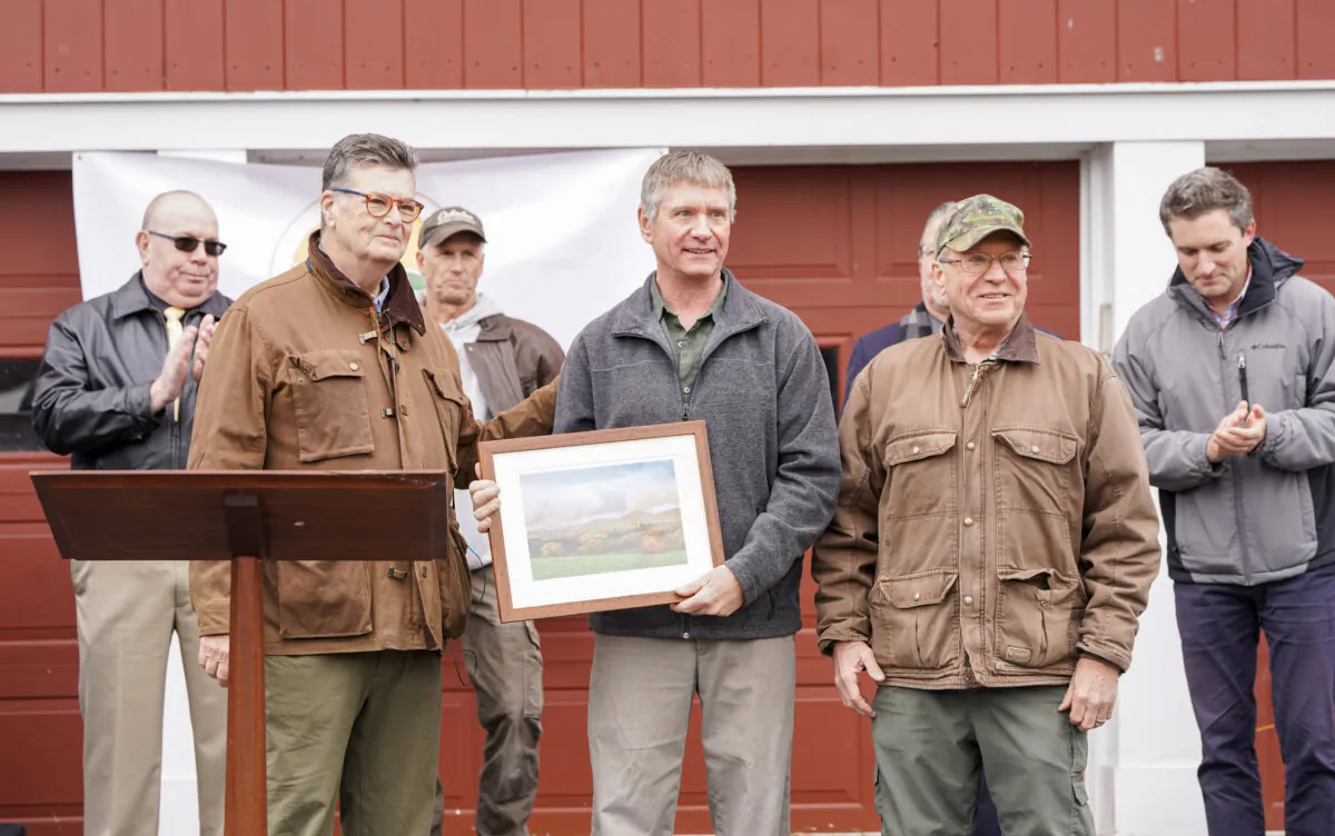 Orange County Land Trust Executive Director Jim Delaune (L) presents a picture of Sugar Loaf Mountain to Chris Palmer, a representative of the Palmer family, in Chester, N.Y., on Jan. 11, 2024. (Cara Ding/The Epoch Times)