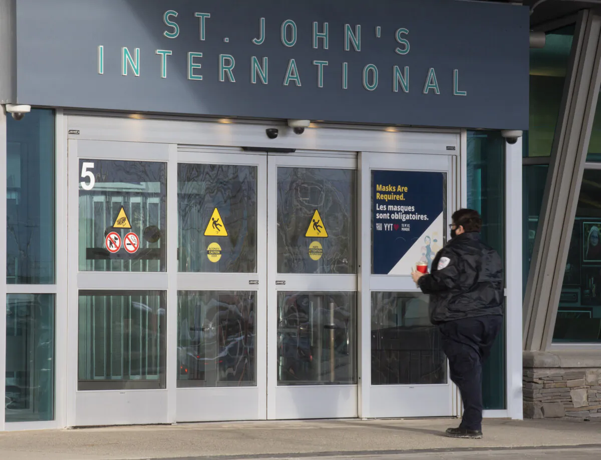 A person standing at the main entrance to St. John's International Airport Terminal is shown on Jan. 19, 2022.  (Paul Daly /The Canadian Press)