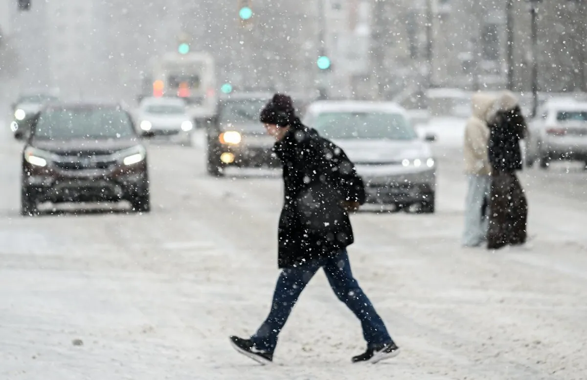A person crosses a street as snow falls in Montreal, on Jan. 7, 2024. (The Canadian Press/Graham Hughes)
