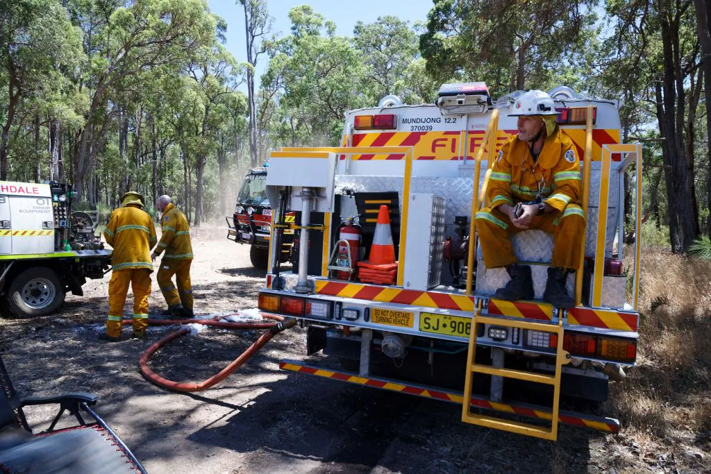 A firefighter sits on his tanker truck awaiting further instructions as the team conduct mop up operations after a bushfire that threatened homes was extinguished in the suburbs of Perth on Feb. 2, 2022. (TREVOR COLLENS/AFP via Getty Images)