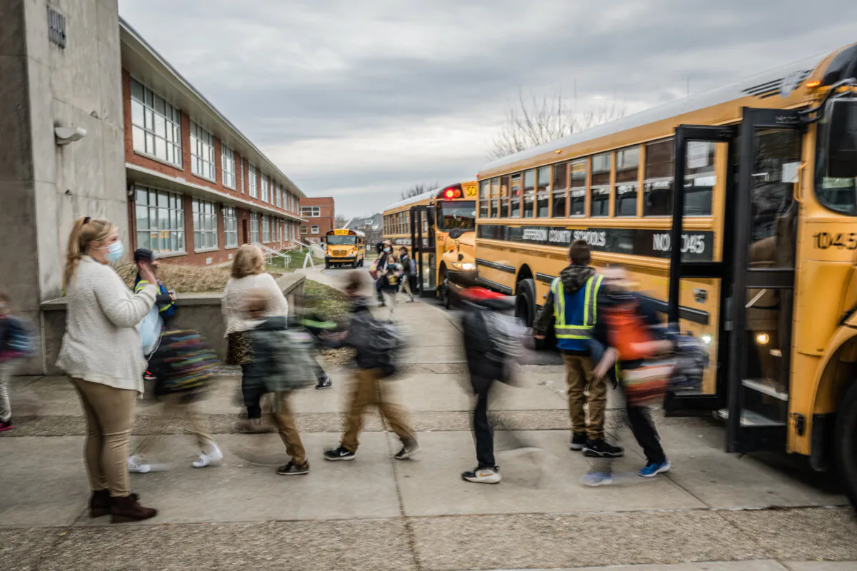 A teacher waves to her students as they get off the bus at Carter Traditional Elementary School in Louisville, Ky., on Jan. 24, 2022. (Jon Cherry/Getty Images)