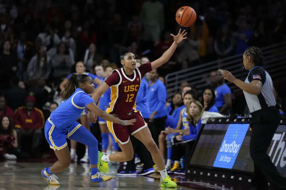 Southern California guard JuJu Watkins (12) tries to keep the ball inbounds against UCLA guard Londynn Jones, left, during the second half of an NCAA college basketball game in Los Angeles on Jan. 14, 2024. (Ashley Landis/AP Photo)