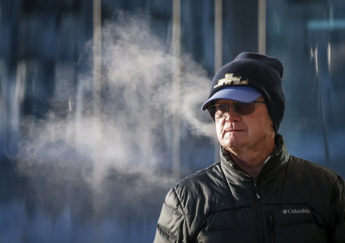 A man walks in the cold trailing a steam cloud in Calgary on Jan. 12, 2024. (The Canadian Press/Jeff McIntosh)
