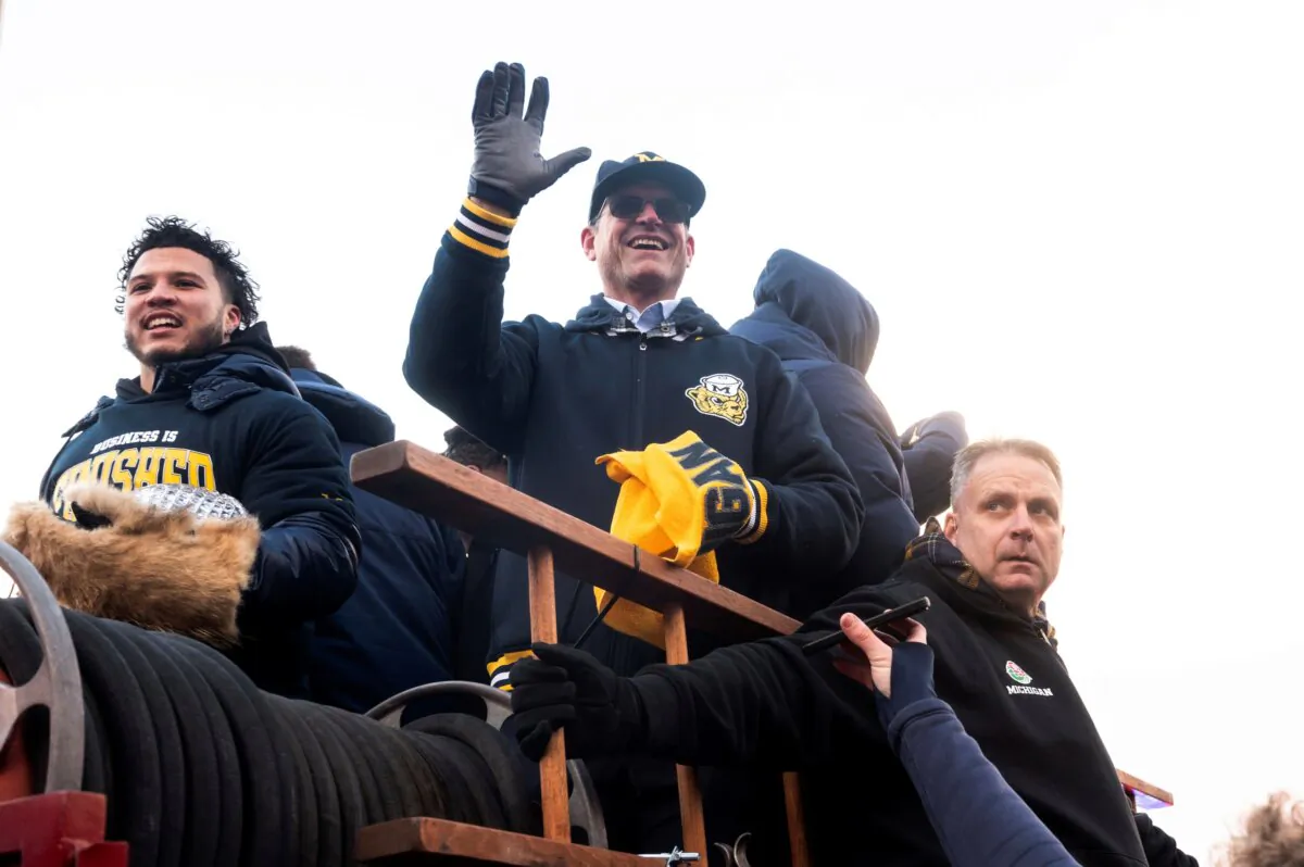 Michigan running back Blake Corum and coach Jim Harbaugh ride a firetruck during a parade celebrating Michigan's college football title, in Ann Arbor, Mich., on Jan. 13, 2024. (Jacob Hamilton/Ann Arbor News via AP)