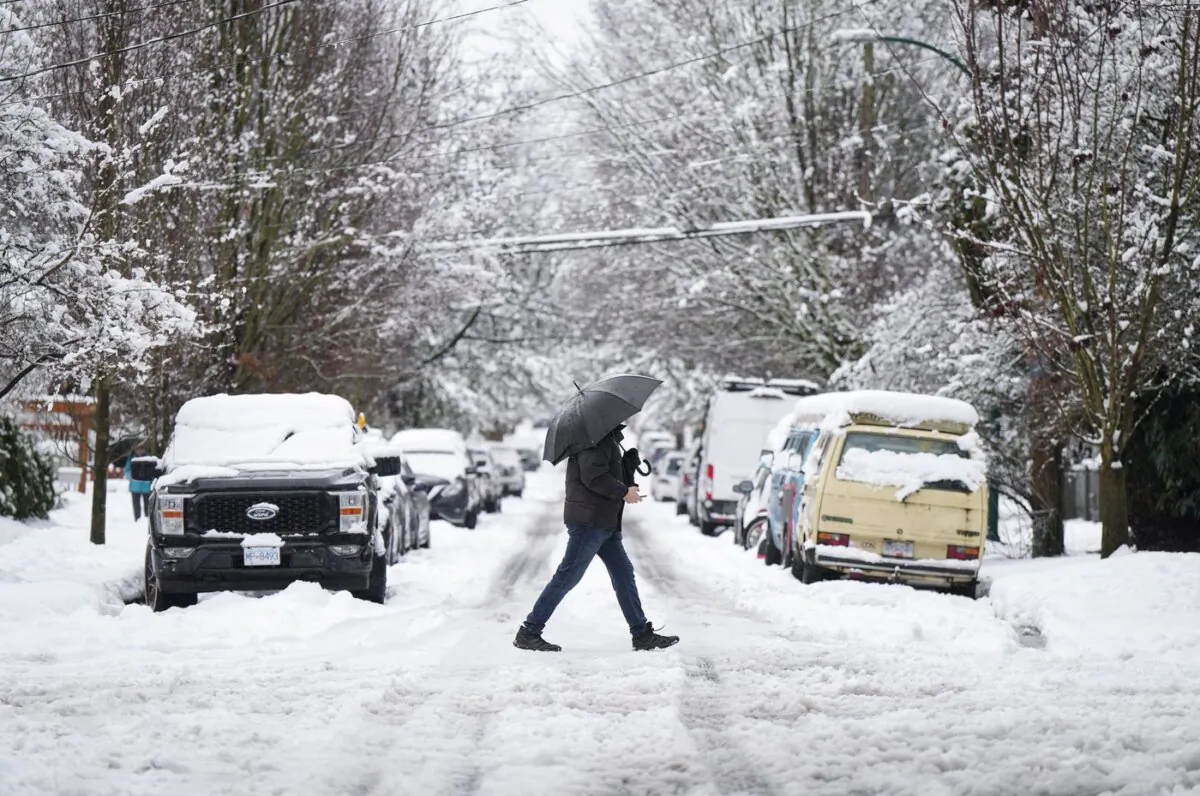 A pedestrian crosses a street after a snowstorm in Vancouver, B.C., on Feb. 28, 2023. (The Canadian Press/Darryl Dyck)