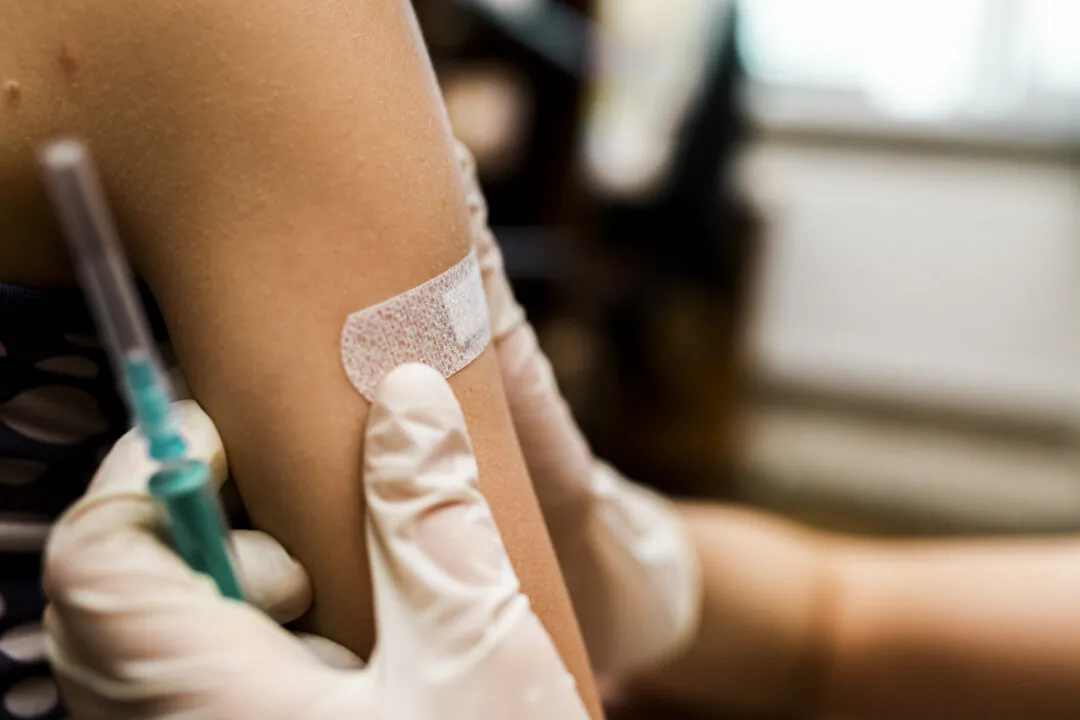 Little girl with band aid on the shoulder from the injection. Vaccinated in the arm. Prevention of children diseases through vaccination. Health care and medicine concept. Focus on shoulder.