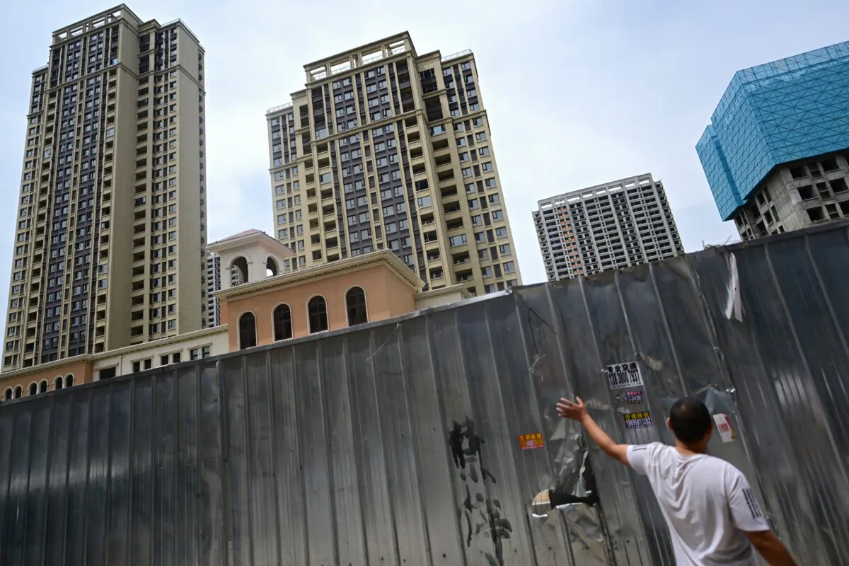 A man standing by a barrier at a complex of unfinished apartment buildings in Xinzheng City in Zhengzhou, China's central Henan province, on June 20, 2023. (Pedro PARDO / AFP)