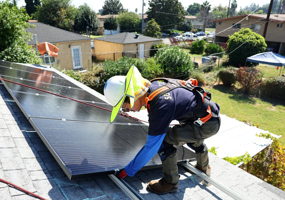 A worker installs solar panels on the rooftop of a house in Pomona, Calif., on Oct. 19, 2023. (Mario Tama/Getty Images)