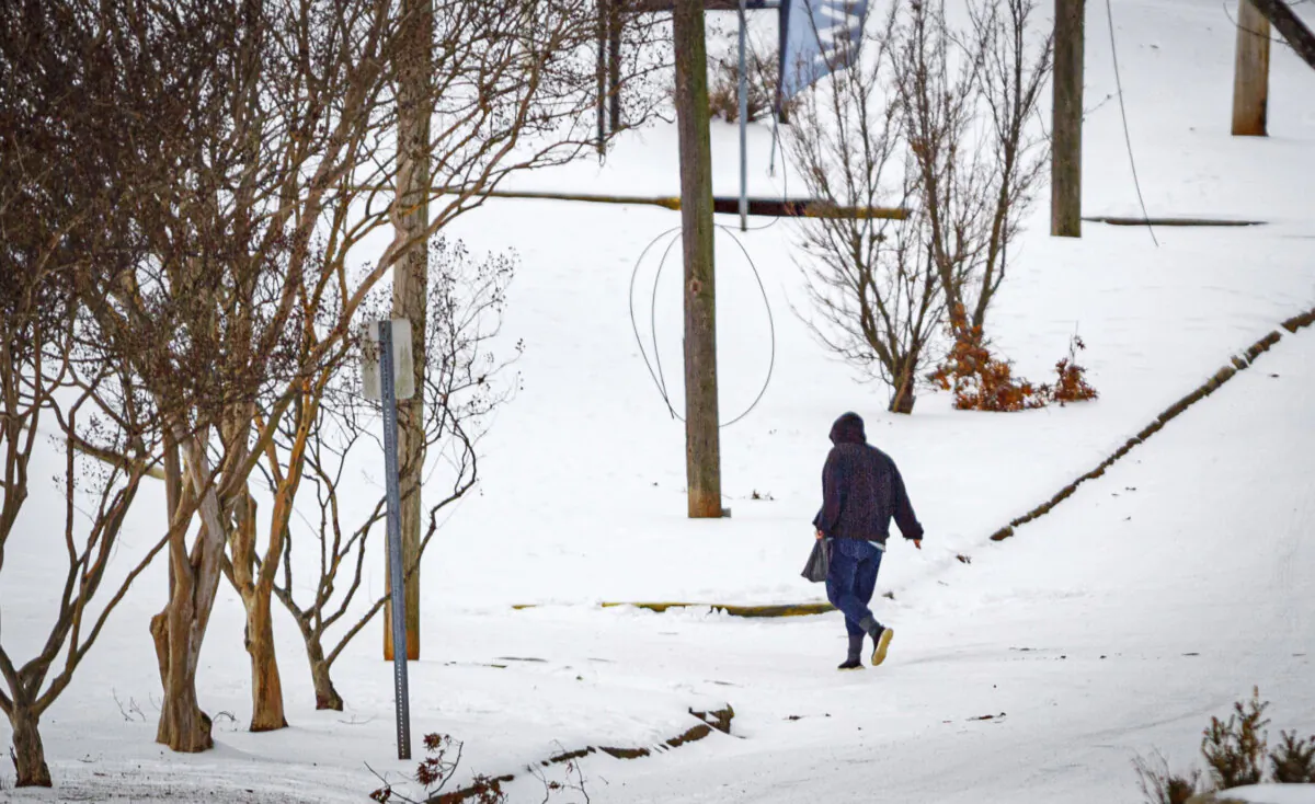 A person crosses in icy conditions in snow while walking over West Tennessee Street in downtown Florence, Ala., on Jan. 18, 2024. (Dan Busey/The TimesDaily via AP)