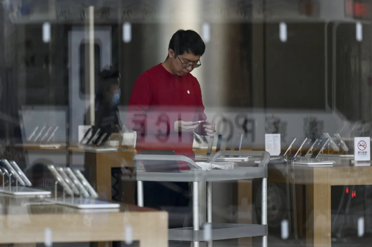 An Apple Store employee prepares for the opening of business in Beijing on Dec. 6, 2023. (Wang Zhao/AFP via Getty Images)