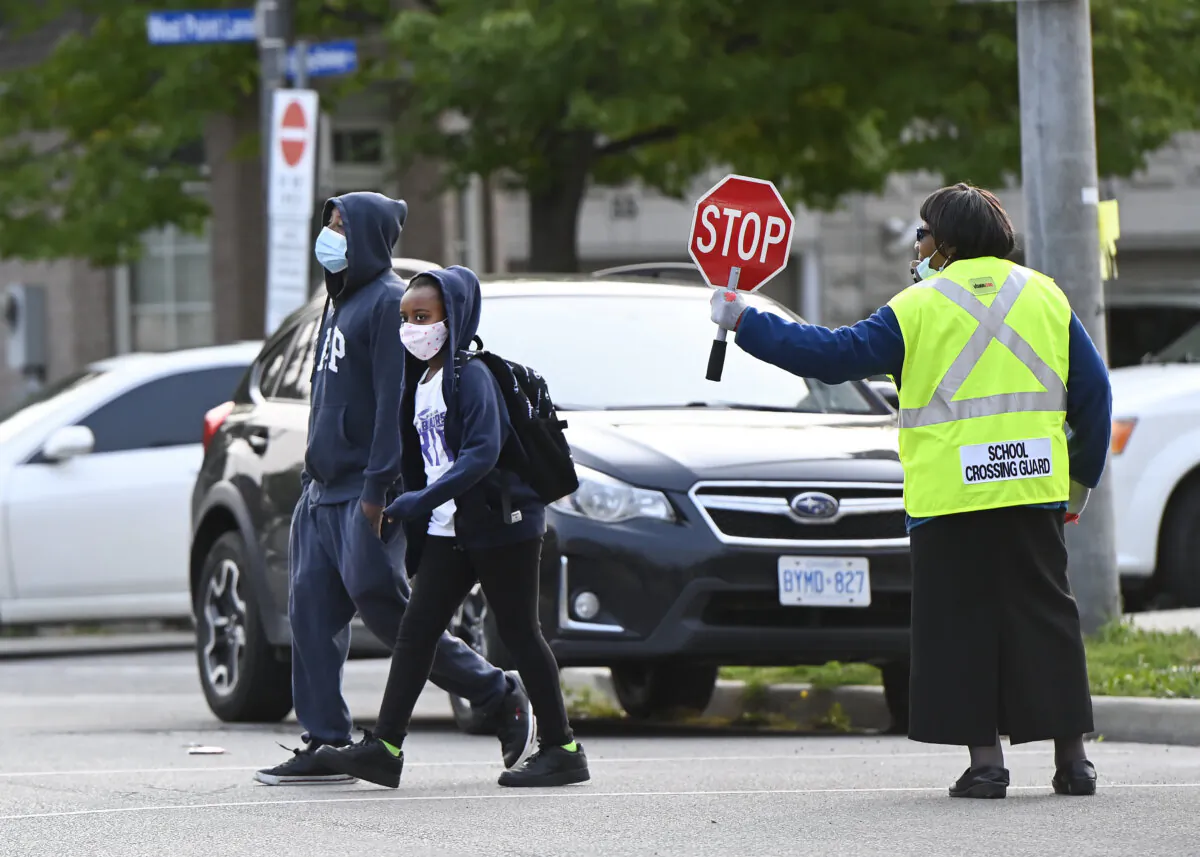 Children cross the street on the way to Portage Trail Community School, part of the Toronto District School Board, in Toronto on Sept. 15, 2020. (The Canadian Press/Nathan Denette)