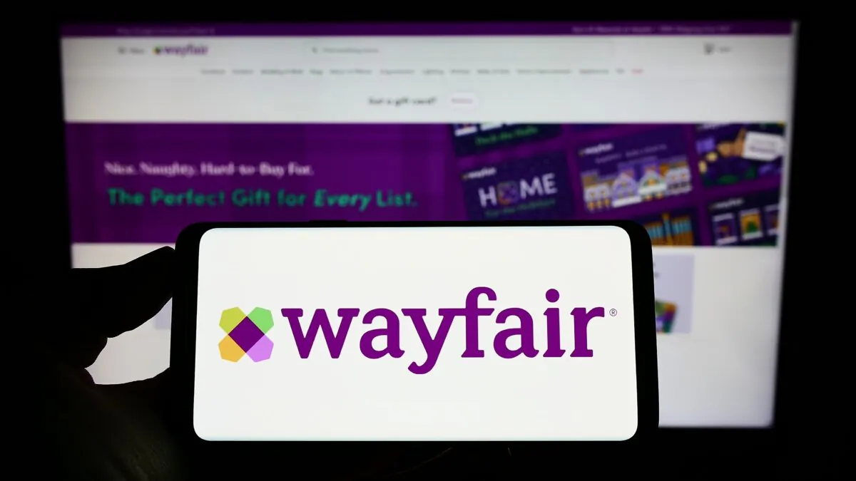 A person holds a smartphone with the logo of US e-commerce company Wayfair Inc. on screen in front of the website in Stuttgart, Germany, on Aug. 28, 2022. (T. Schneider/Shutterstock)