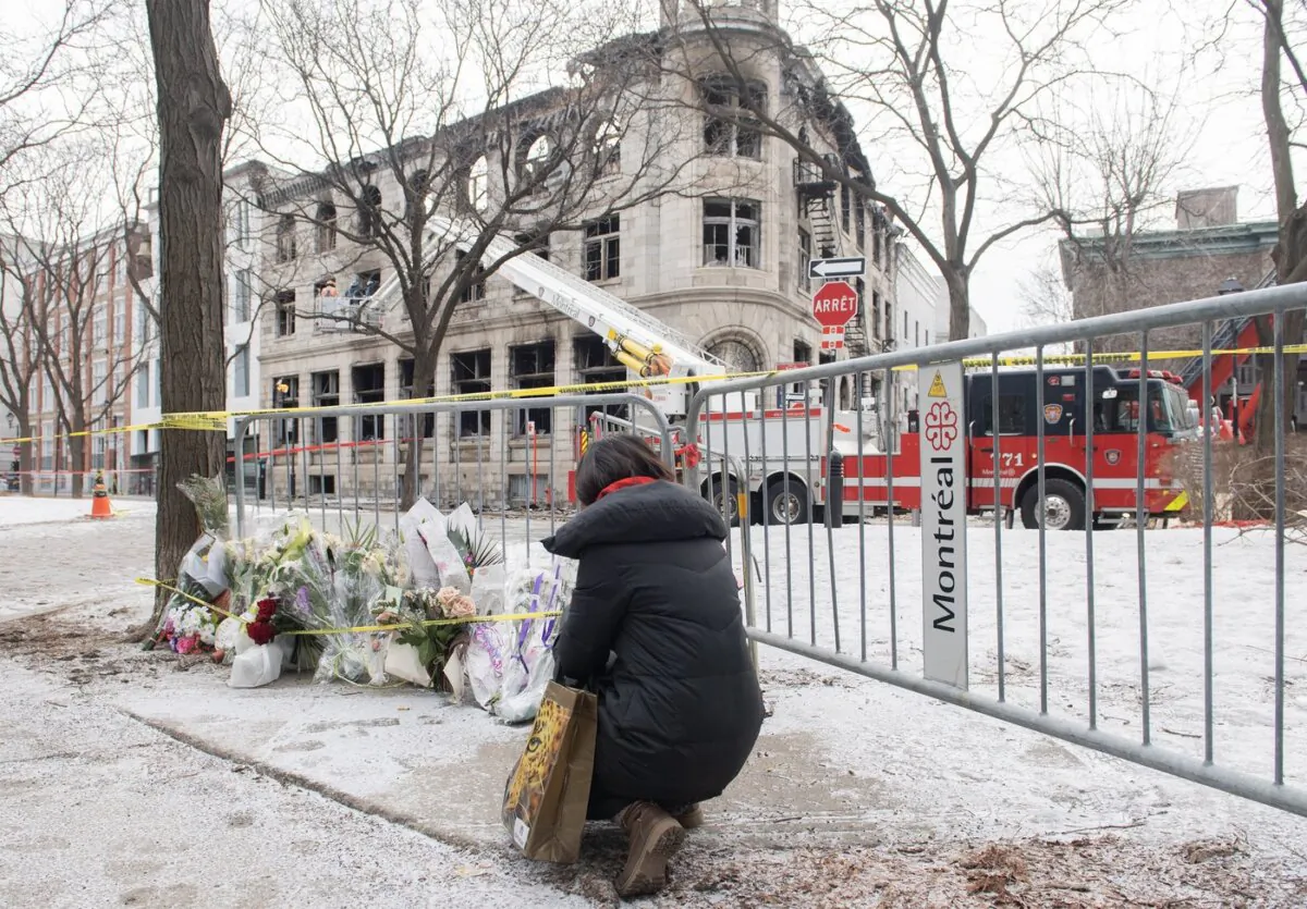 A woman kneels next to a makeshift memorial at the scene following a fire in Old Montreal, on March 19, 2023. (The Canadian Press/Graham Hughes)