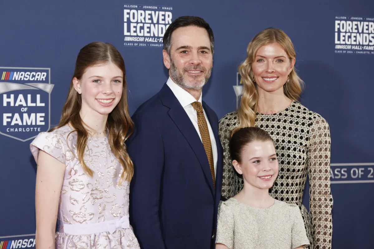 Jimmie Johnson, second from left, stands with his wife Chandra Janway, top right, and daughters Genevieve, left, and Lydia, front right, at his induction into the NASCAR Hall of Fame in Charlotte, N.C., on Jan. 19, 2024. (Nell Redmond/AP Photo)