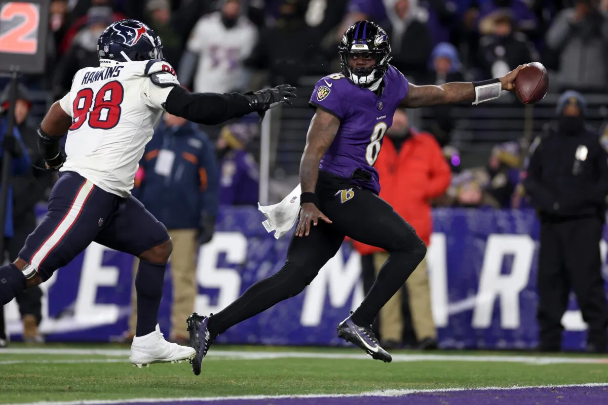Lamar Jackson (8) of the Baltimore Ravens scores an 8 yard touchdown against Sheldon Rankins (98) of the Houston Texans during the fourth quarter in the AFC Divisional Playoff game in Baltimore on Jan. 20, 2024. (Patrick Smith/Getty Images)