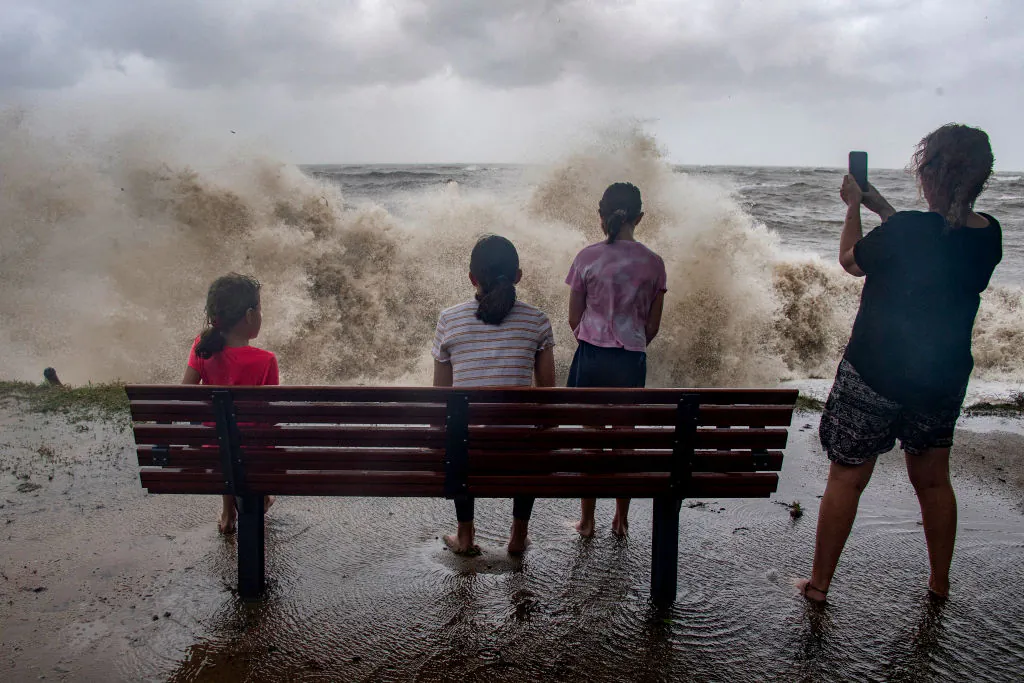 A family watch the storm roll in across the Coral Sea at Holloways Beach as Cyclone Jasper approaches landfall in Cairns in far north Queensland on Dec. 13, 2023. (BRIAN CASSEY/AFP via Getty Images)