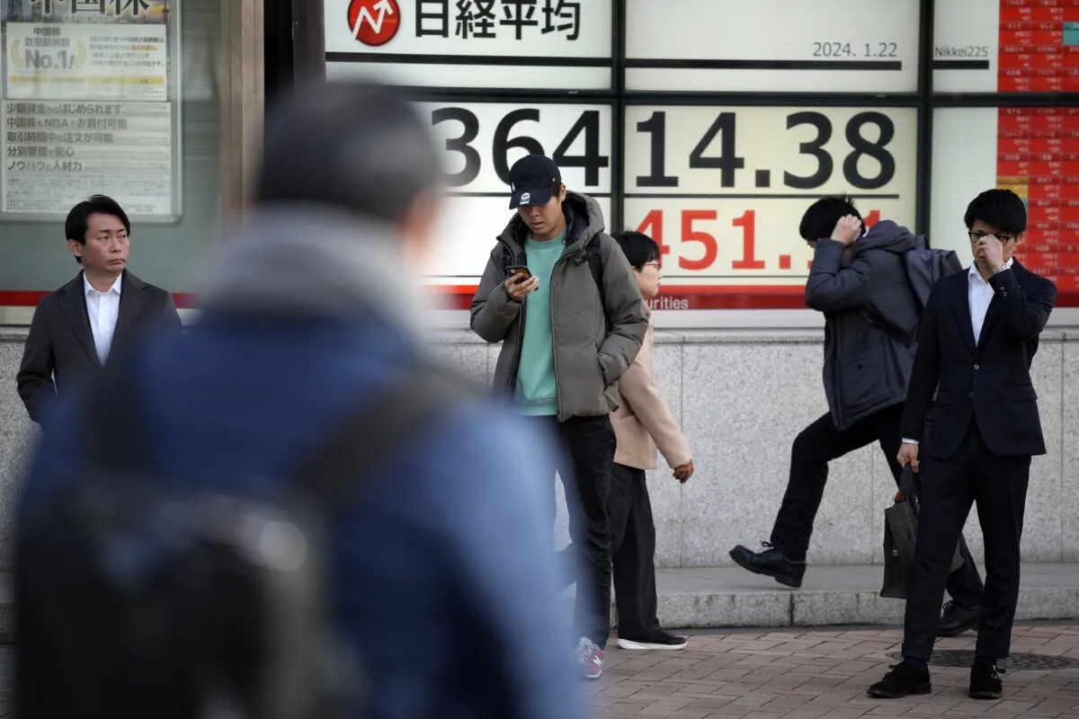 People stand near an electronic stock board showing Japan's Nikkei 225 index at a securities firm in Tokyo on Jan. 22, 2024. (Eugene Hoshiko/AP Photo)