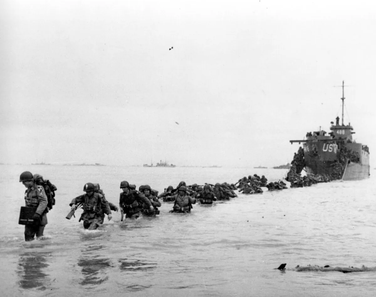 U.S. reinforcements wade through the surf from a landing craft in the days following D-Day and the Allied invasion of Nazi-occupied France at Normandy, in June 1944. (Bert Brandt/Pool via AP)
