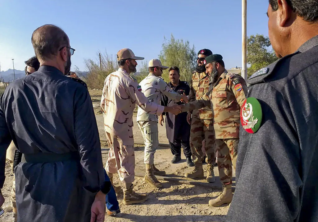 In this picture taken on April 21, 2019, Pakistani border security officials (R) and Iranian border security officials (L) shake hand each others at Zero Point in the Pakistan-Iran border town of Taftan. - Iran and Pakistan have agreed to set up a joint border "reaction force" following a number of deadly attacks by militant groups on their frontier, Iranian President Hassan Rouhani announced April 22 after talks with visiting Pakistani Prime Minister Imran Khan. (Photo by STR / AFP) (Photo by STR/AFP via Getty Images)