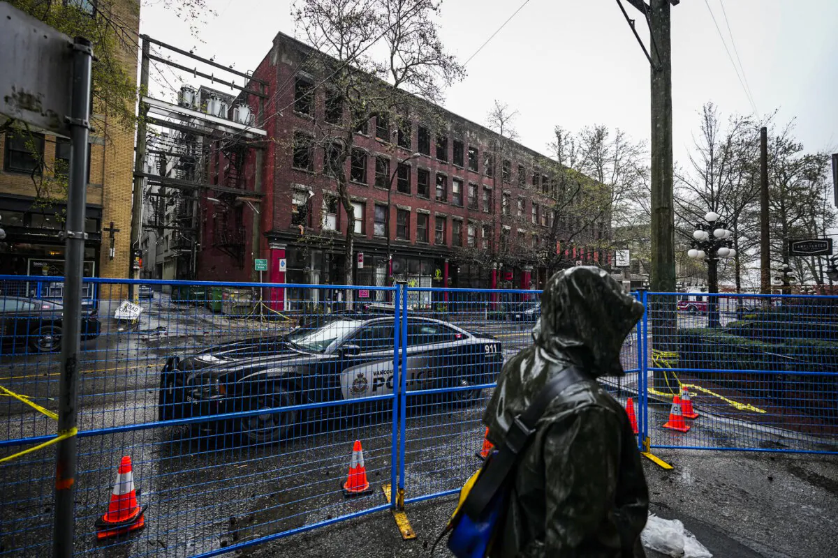 A police officer sits in a vehicle outside of the Winters Hotel that was destroyed by fire in Vancouver on April 12, 2022. (The Canadian Press/Darryl Dyck)