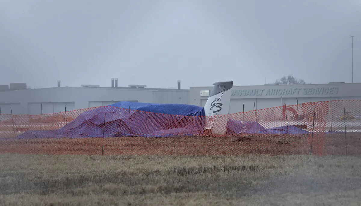The wreckage of a single-engine Cirrus SR 22 aircraft is covered by a blue tarp near a runway at the Bill and Hillary Clinton National Airport in Little Rock, Ark., on Jan. 22, 2024. (Colin Murphey/Arkansas Democrat-Gazette via AP)