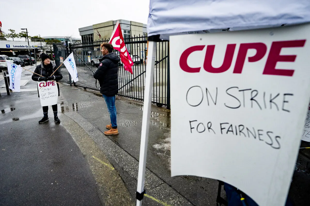 Transit workers from the Canadian Union of Public Employees Local 4500 picket outside of the Lonsdale SeaBus station in the rain during a strike in North Vancouver, B.C., on Jan. 22, 2024. (The Canadian Press/Ethan Cairns)